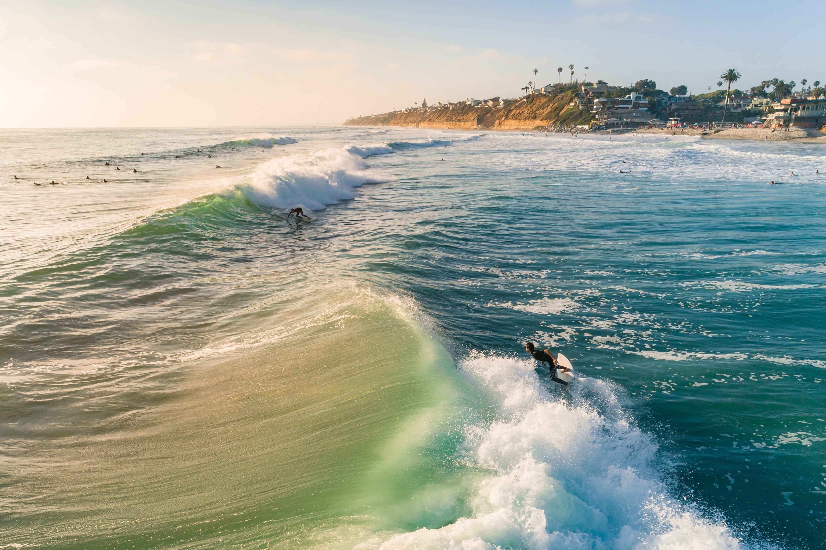 Vibrant Encinitas coastline sunset with palm trees and couple carrying surfboards